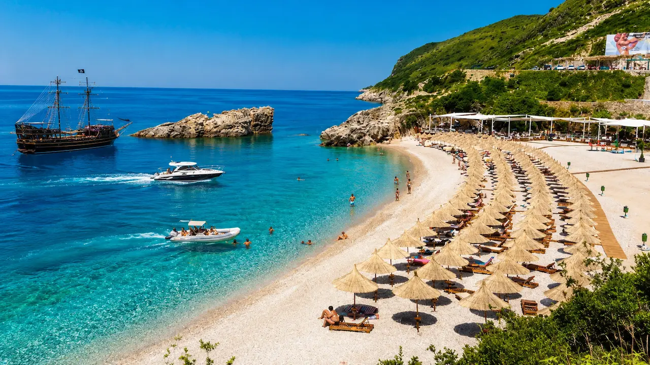 Jale Bay in Himare with pirate ship, luxury speedboat and crystal clear turquoise water