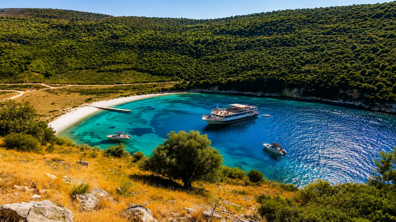 Boat trip Sarande visiting Kakome Bay with tour boats and crystal-clear turquoise water